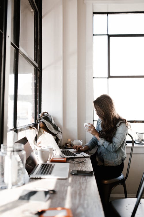 Mujer trabajando con un portátil junto a una ventana – Servicios fiscales para emprendedores