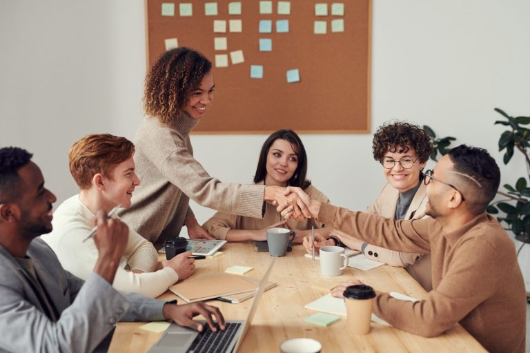 Equipo en una reunión estrechándose la mano – Nóminas y Seguridad Social
