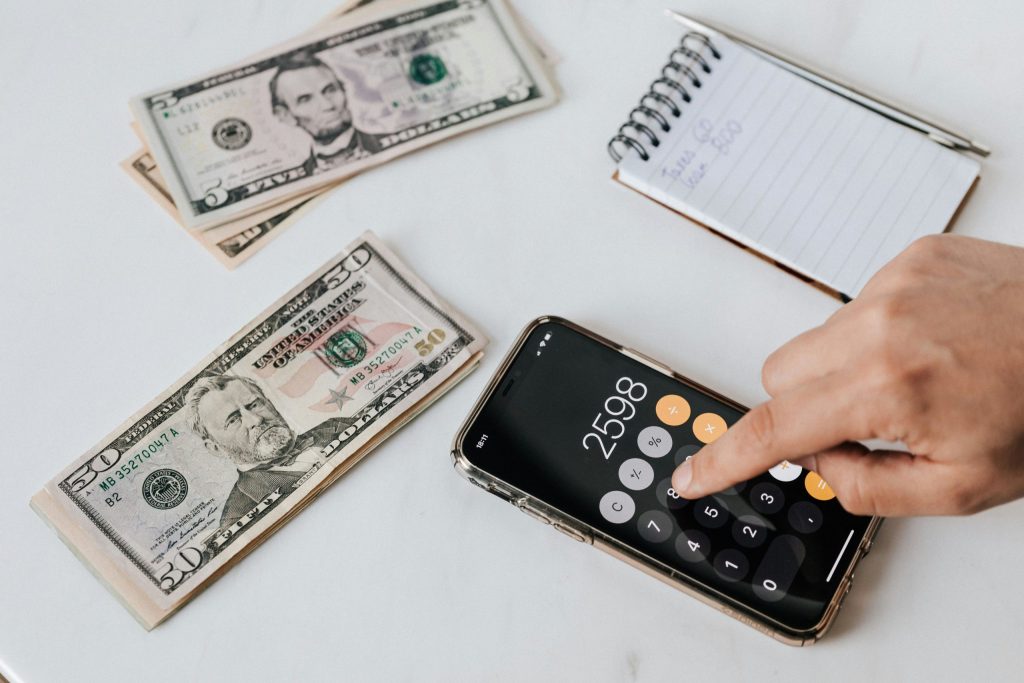 Mano con una calculadora junto a billetes y un cuaderno – Nóminas y Seguridad Social