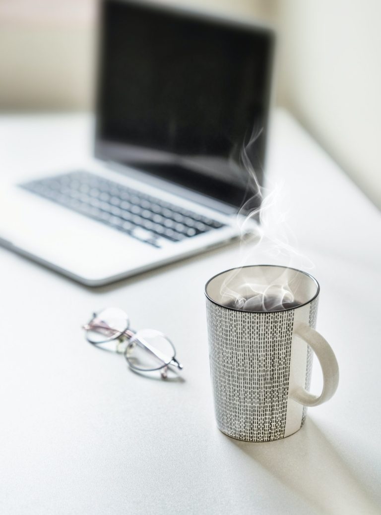 Portátil y taza sobre una mesa en casa – Guía de gastos deducibles de un autónomo