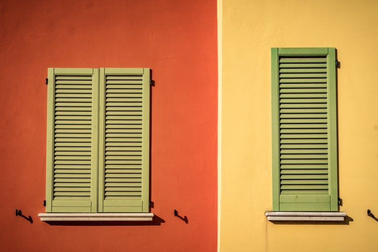 Ventanas con postigos verdes en una fachada naranja – Proceso de hipoteca