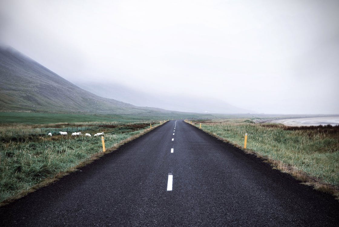 Carretera recta hacia las montañas con niebla