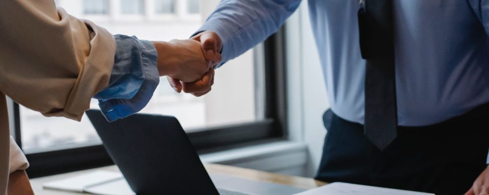 Dos personas estrechan la mano en una reunión de trabajo